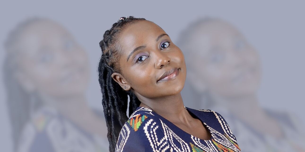 A portrait of Ann-Waithaka on a grey background. Ann is a Black woman with long dark hair who is wearing a navy top with white and grey patterns