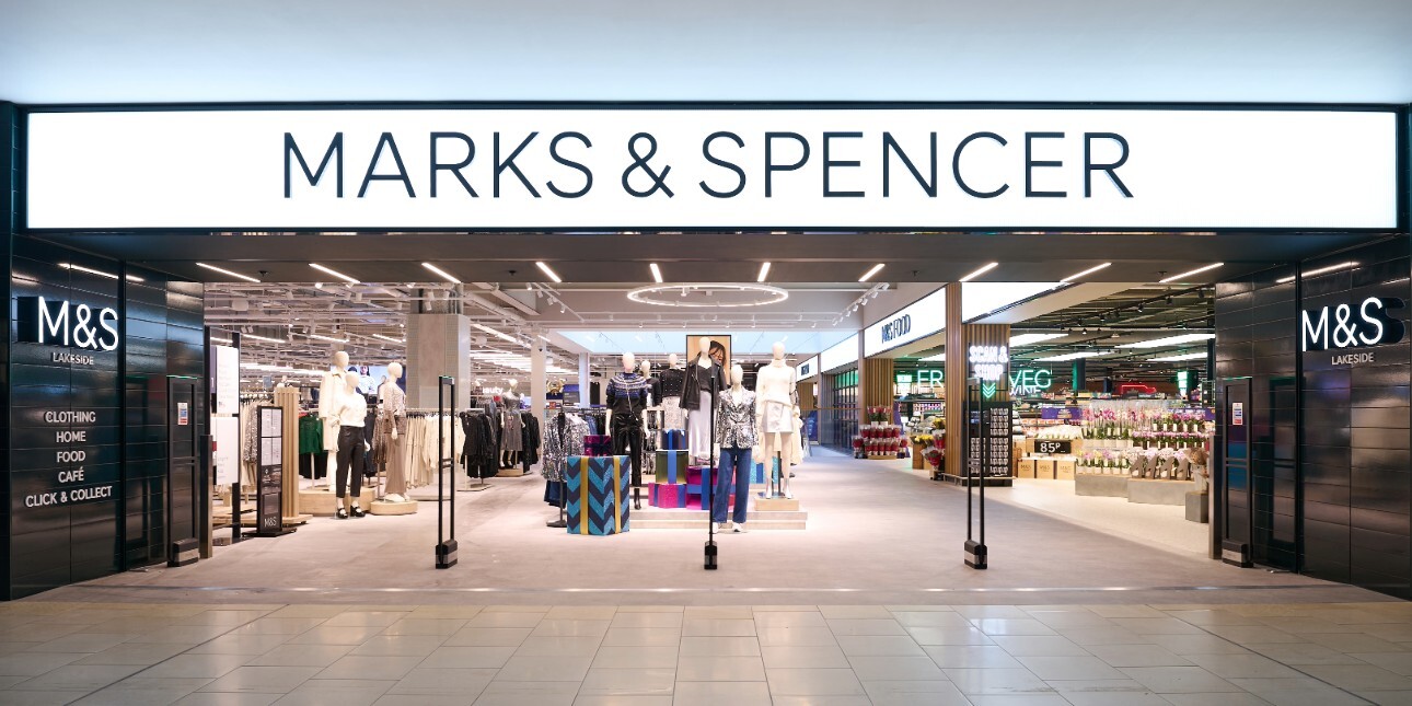 The wide entrance of a Marks and Spencer store with the brand name above the doorway and mannequins wearing women's clothes in the background