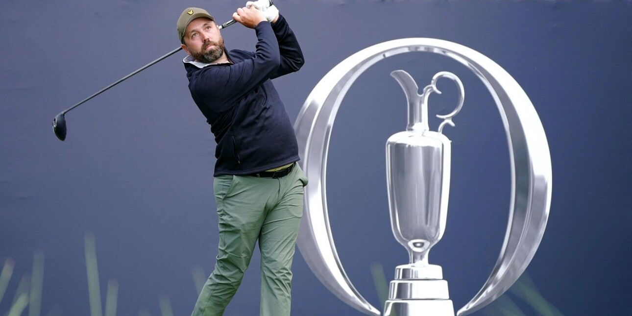 Golf influencer Rick Shiels tees off. He is a white man with a beard who wears a green cap, blue top and green trousers. He is in front of the a blue hoarding with a silver emblem.