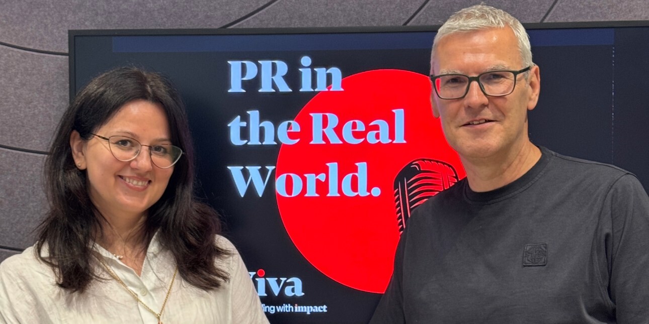 Julia Petryk and Tony Garner in front of a screen displaying the words PR in the Real World. Julia is a white woman with dark hair and glasses, wearing a beige top. Tony is a white man with blond hair and glasses wearing a grey top.