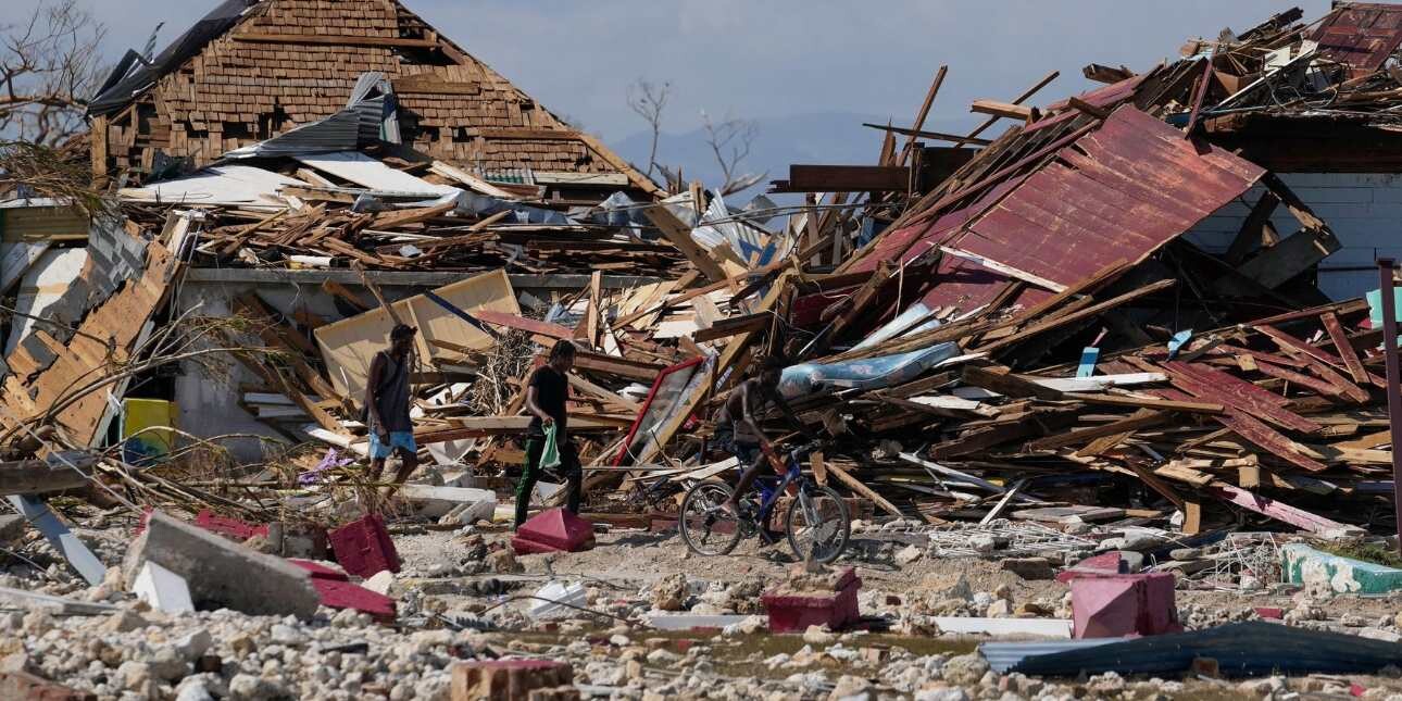 Two people surrounded by collapsed wooden buildings and debris