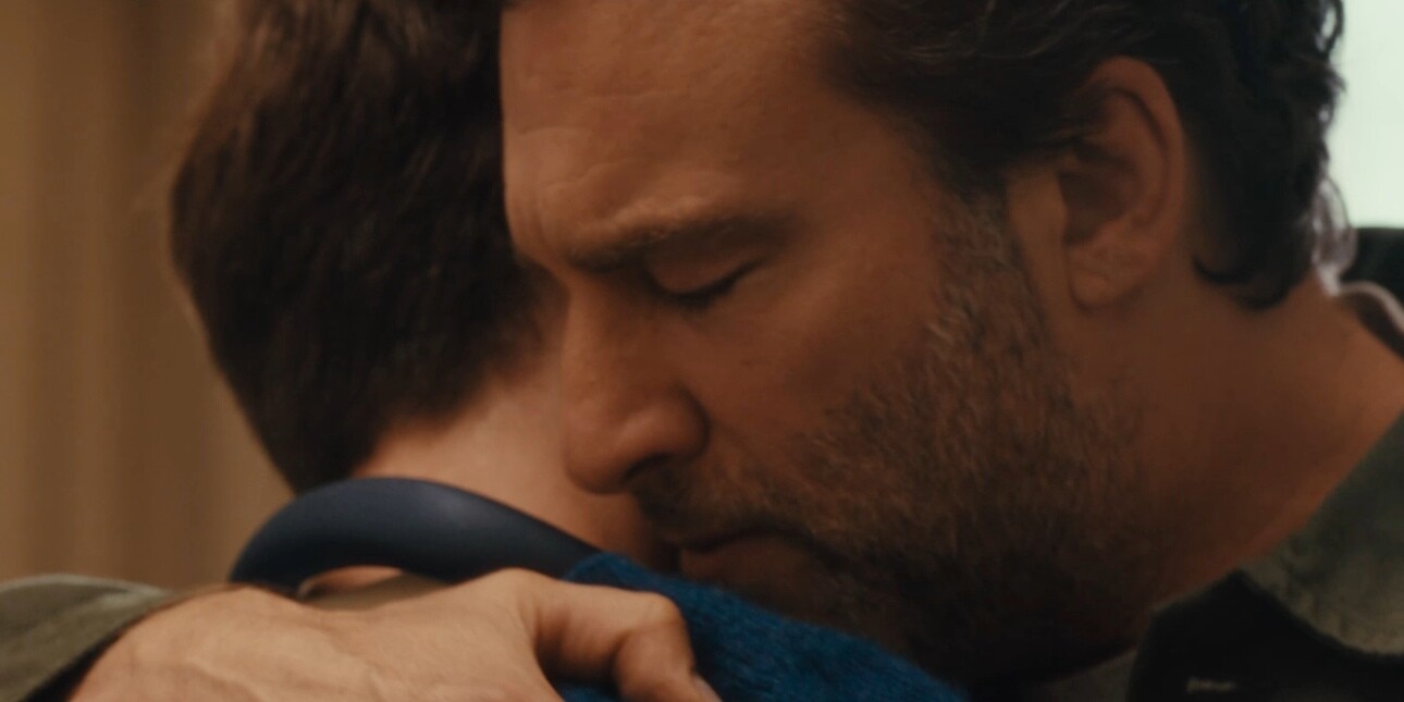 A still from the John Lewis Christmas advert showing a close-up of a white man with dark hair embracing his son, who is also white with dark hair.