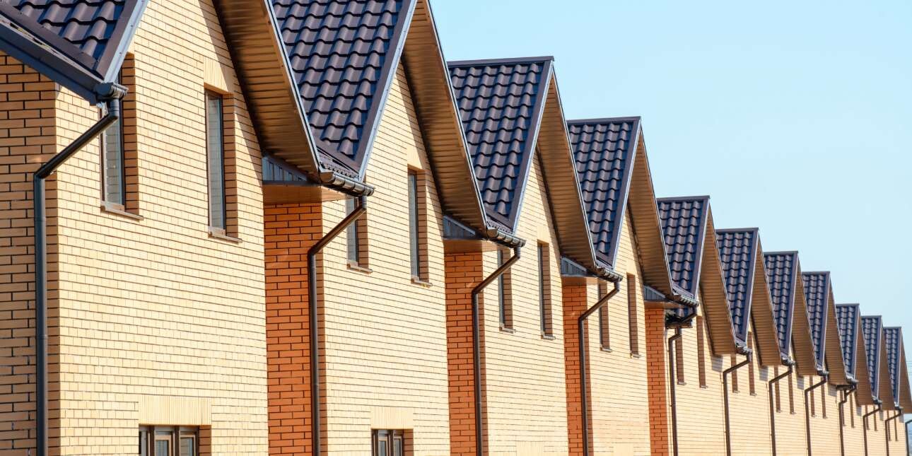 The roof line and upper storey of a modern yellow-brick row of houses.