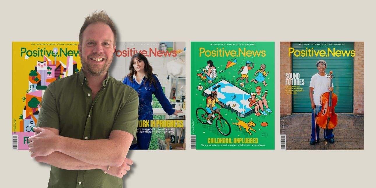 A cut out of a smiling Tom Pattinson placed in front of four covers of Positive News magazine. Tom is a white man with short light brown hair who is stood with his arms crossed and wearing a green shirt.