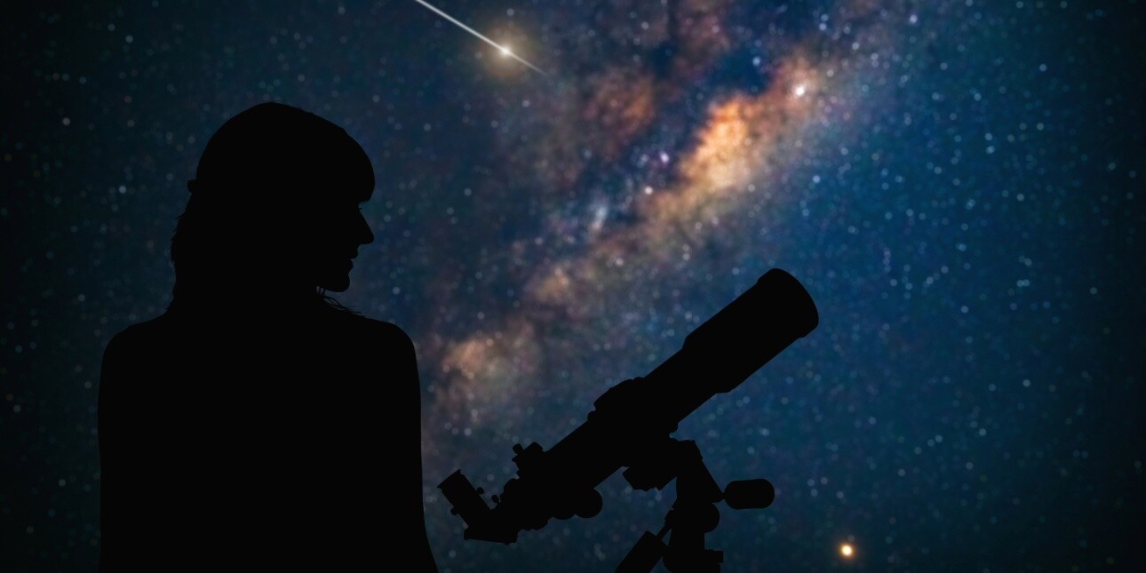 A silhouette of an astronomer and a telescope against a star filled sky