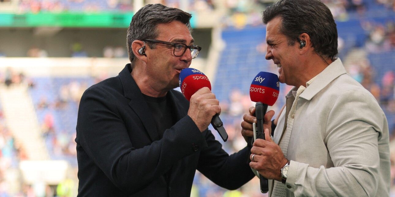 Andy Burnham in light hearted conversation with Brian Carvey on the pitch a rugby league stadium.