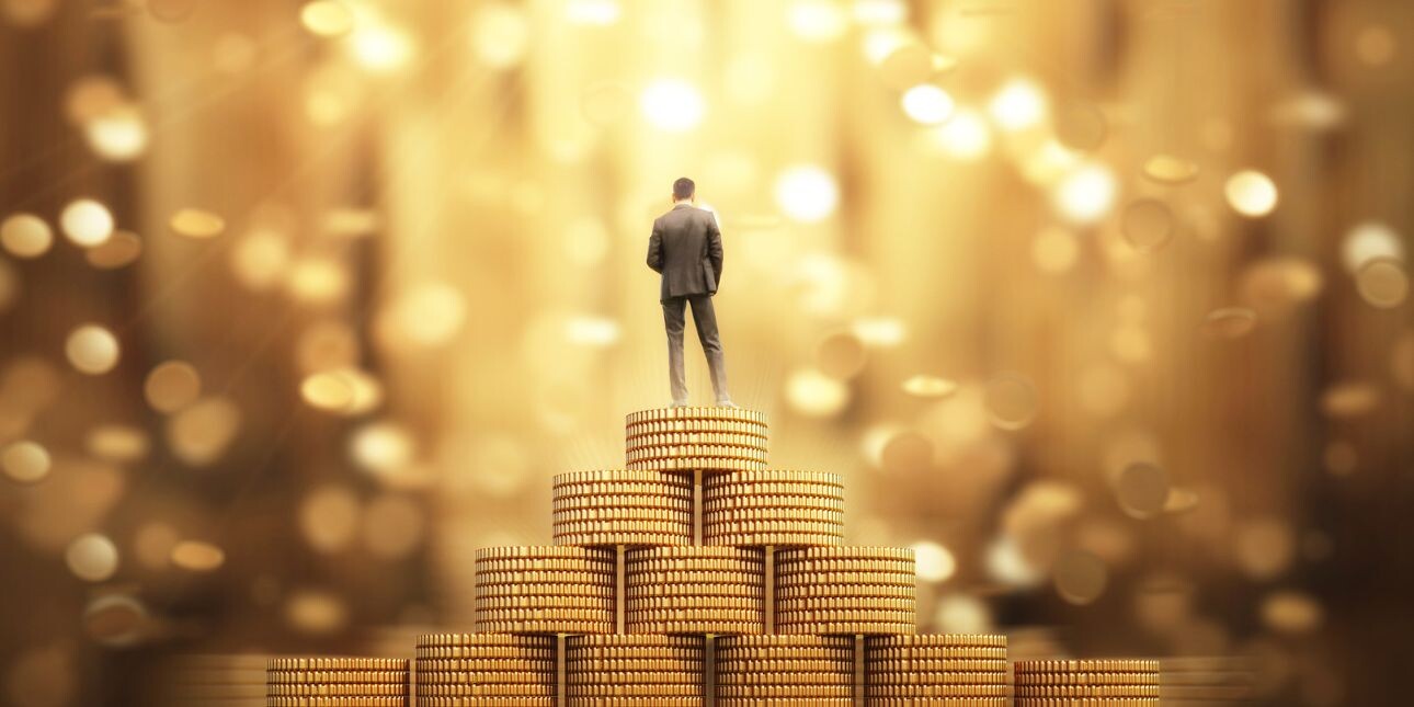 A business person stood on a stack of gold coins.