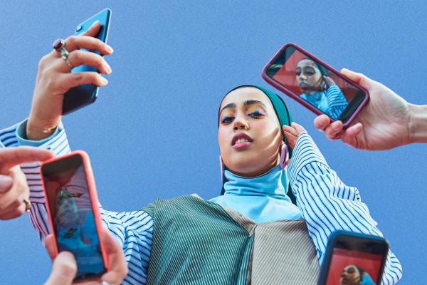 Young woman having picture taken by multiple smartphones.