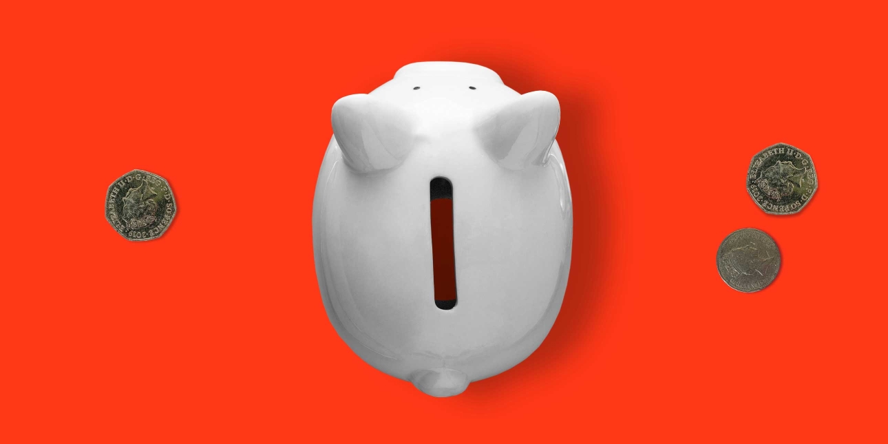 An overhead view of an empty piggy bank with three coins either side.