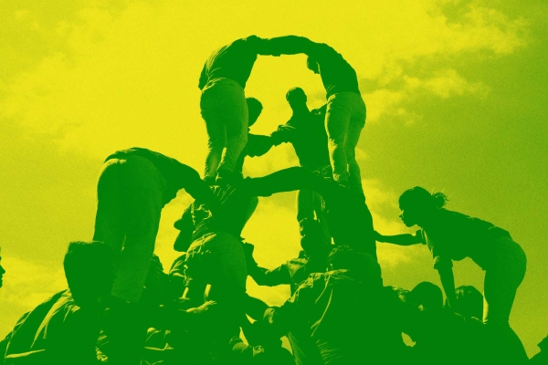 Group of people climbing onto each other shoulders to make a human structure.