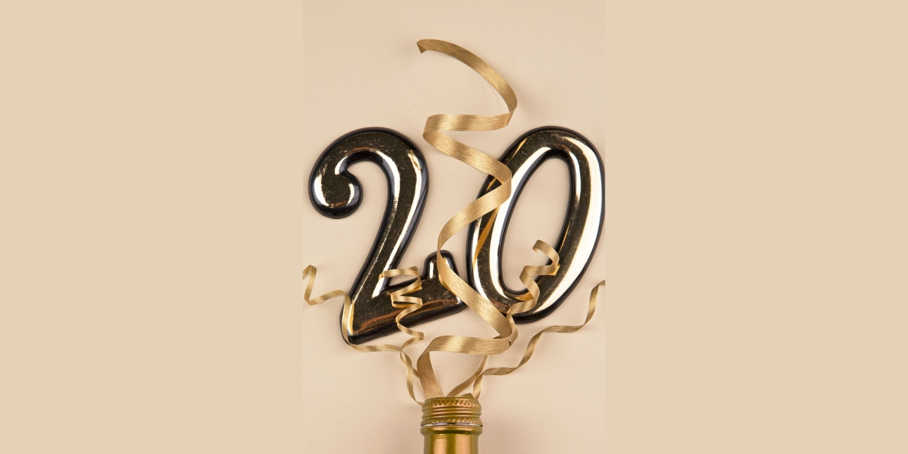 Gold coloured two and zero balloons and streamers popping from a bottle