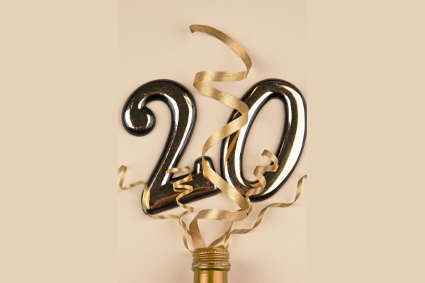 Gold coloured two and zero balloons and streamers popping from a bottle