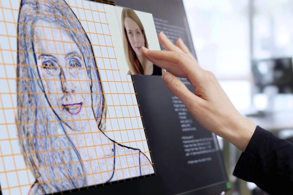 A woman’s hand working on a computer touchscreen. She’s working on an AI virtual model of a young woman.