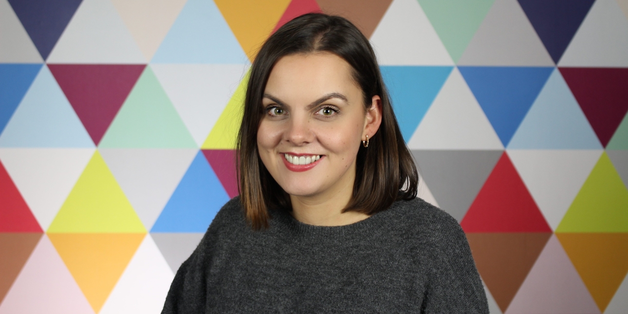 Carly Bannerman, a white woman with dark shoulder length hair, on a background of multicoloured triangles