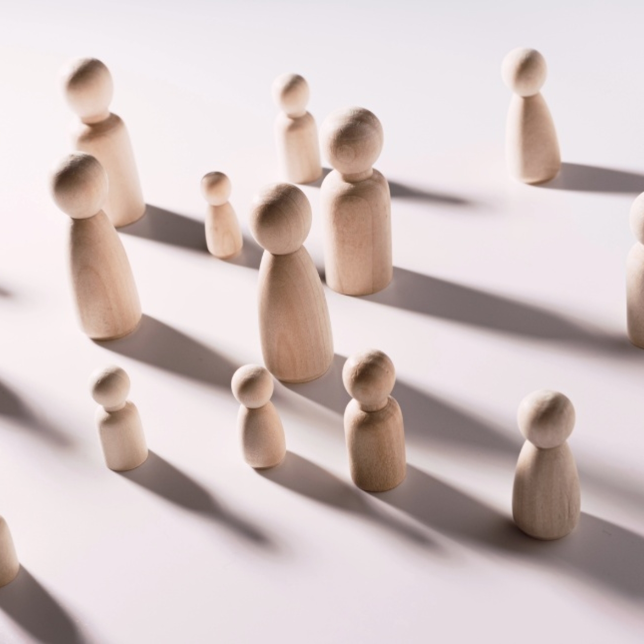 An assortment of different sized wooden figures on a pink background