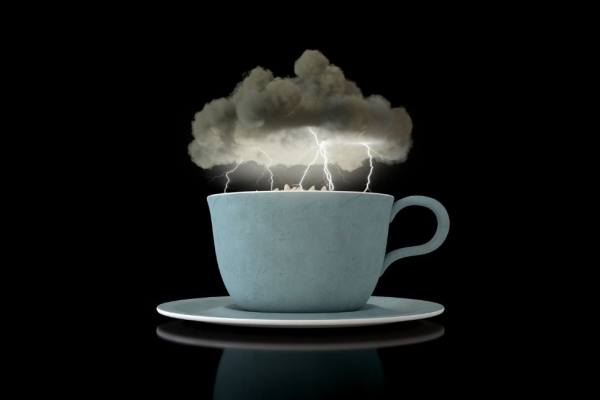 A 3D render a grey storm cloud hovering over a turbulent cup of tea in a blue cup with lightning striking. The background is black.