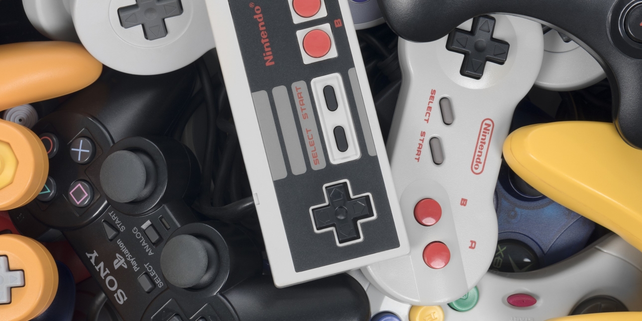 A pile of different sized, shaped and coloured hand held games consoles