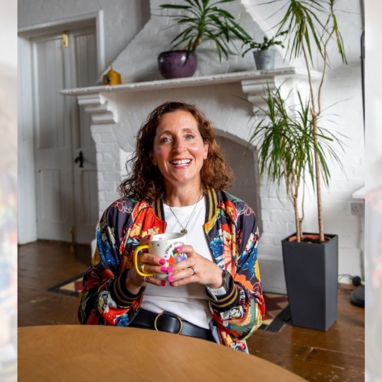 A tryptic of Katie Marlow sat in a chair holding a mug. Katie is a white woman with curly brown hair. She wears a multi-coloured floral jacket. She is sat a table in front of a white brick fireplace and doors