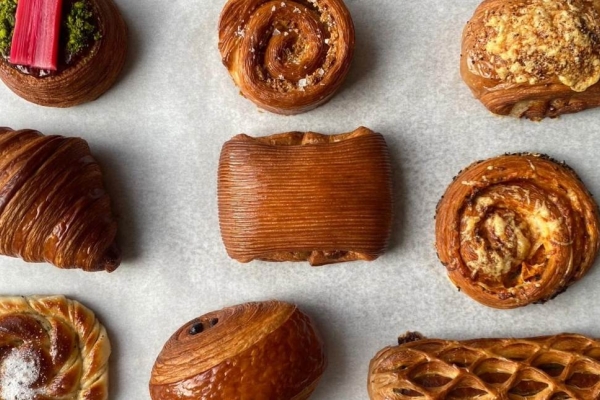 A bird's eye photograph of nine different types of croissant lying on a sheet of greaseproof paper