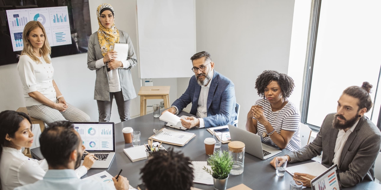 Multi ethnic group of coworkers in office have meeting. They have presentation of business plan.