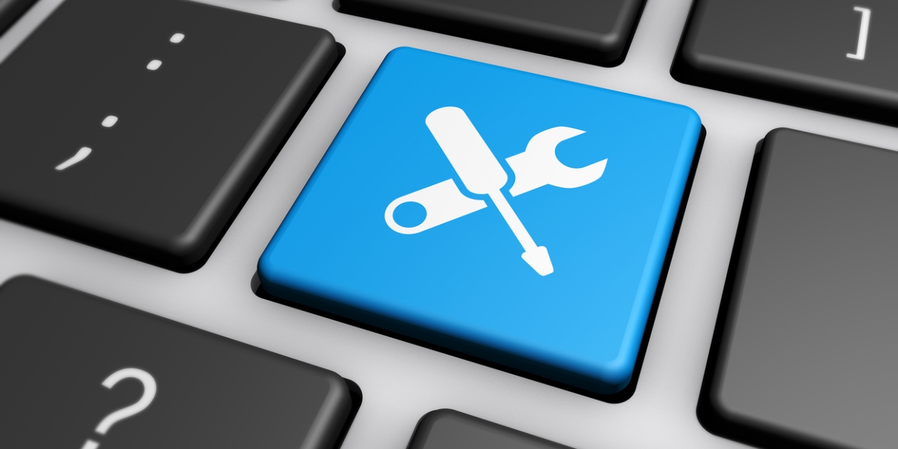 A keyboard key is coloured blue with white overlapping icons of a screwdriver and spanner. It's surrounded by black keys with a question mark, colon and semi colon in white.