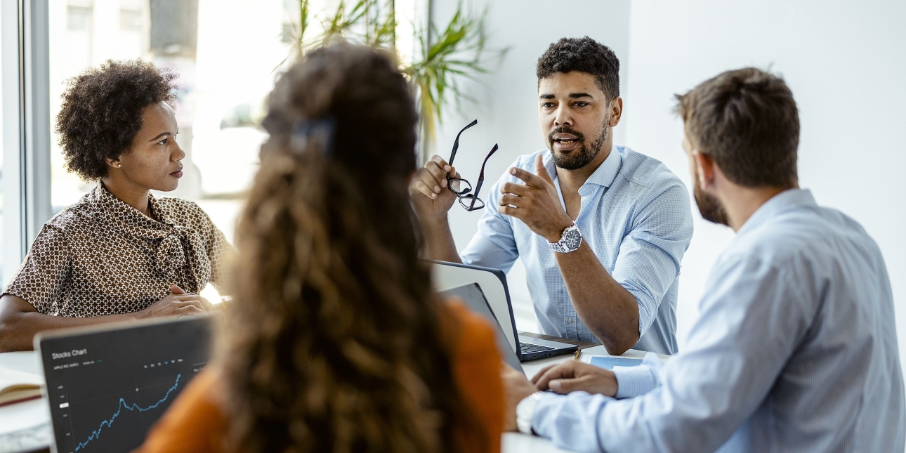Four colleagues of different genders and ethnicities sit around a table in discussion