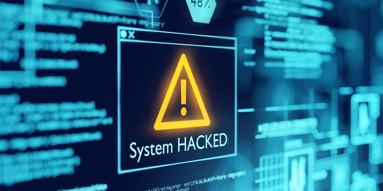 A dark computer screen featuring green machine code type and a large exclamation mark in a yellow triangle with the words system hacked underneath