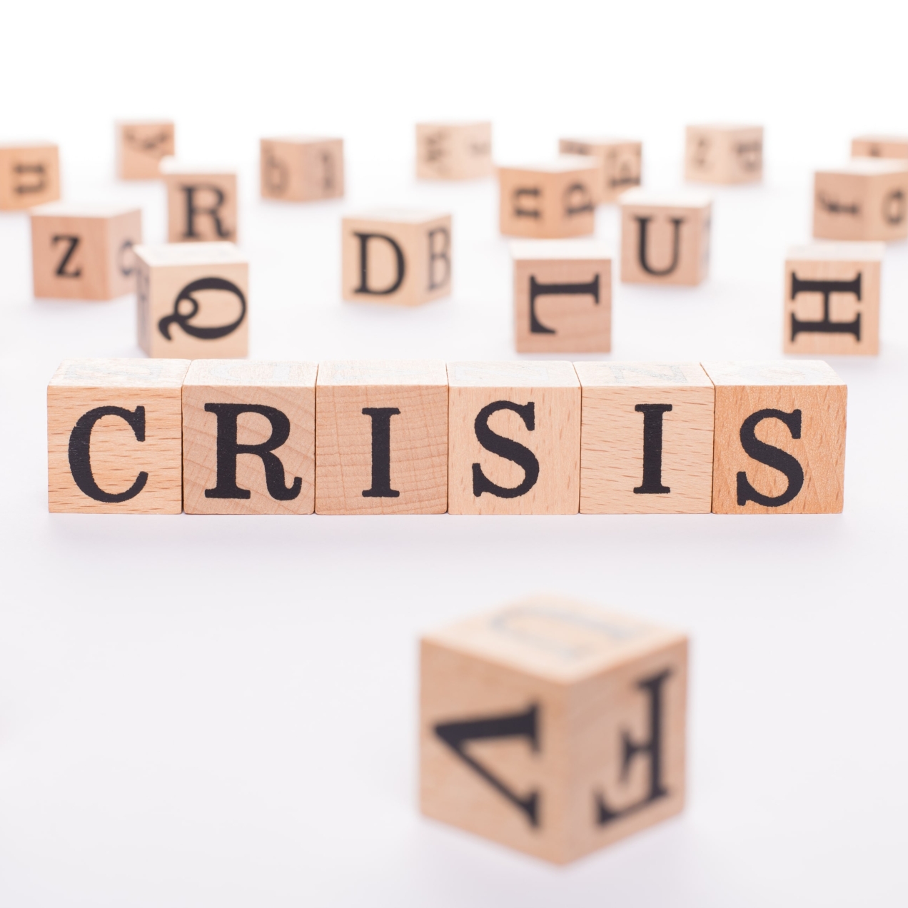The word crisis spelt out on six wooden blocks with other random letters alongside