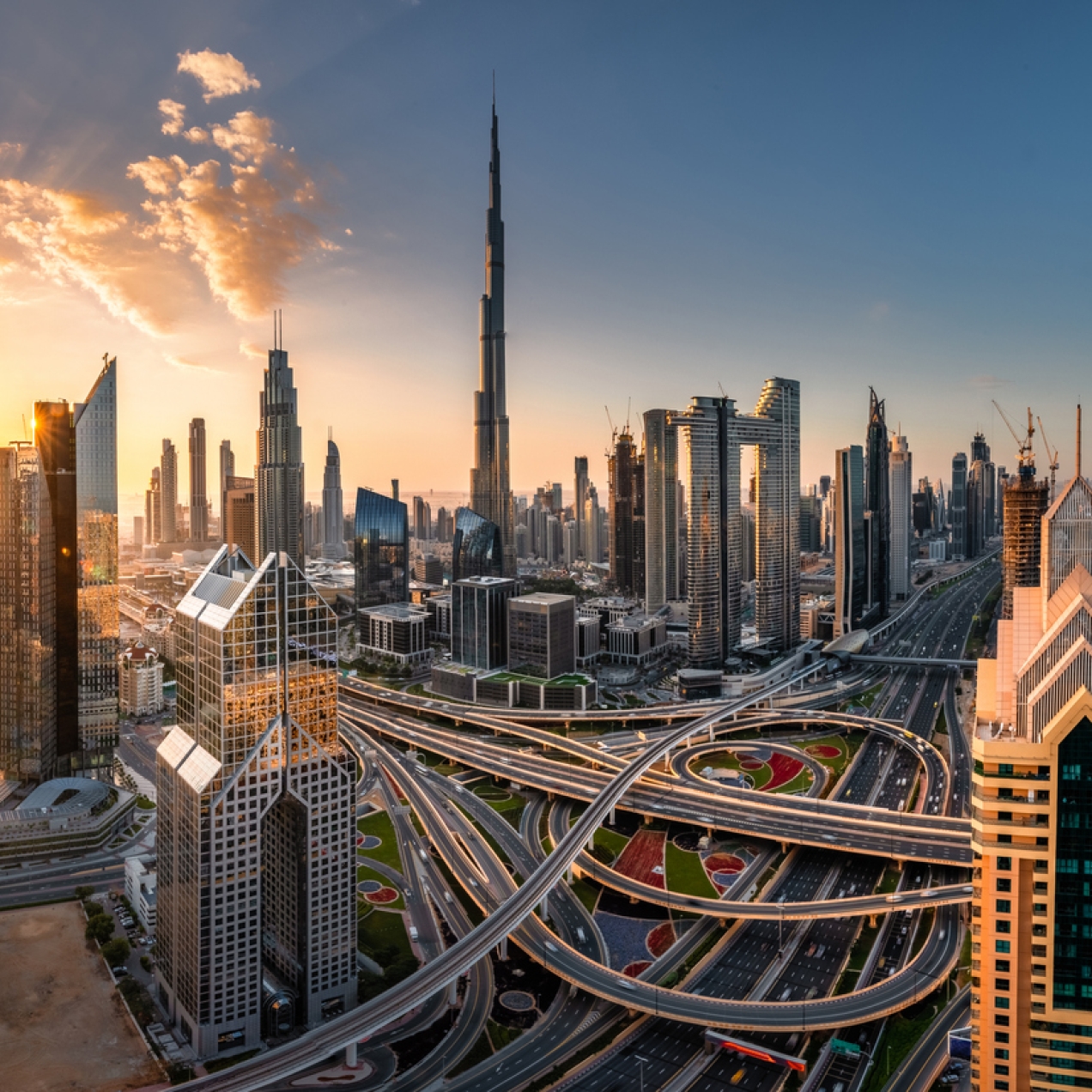 The Dubai skyline with a large swirling highway in the foreground and skyscrapers in the background