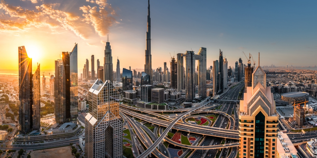 The Dubai skyline with a large swirling highway in the foreground and skyscrapers in the background