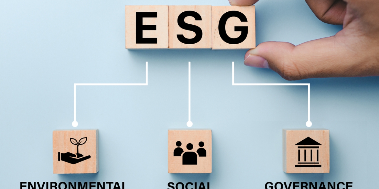 A finger and thumb place a wooden building block featuring the letter G next to blocks featuring E and S. Pen lines link them to three other blocks with icons representing Environmental, Social and Governance