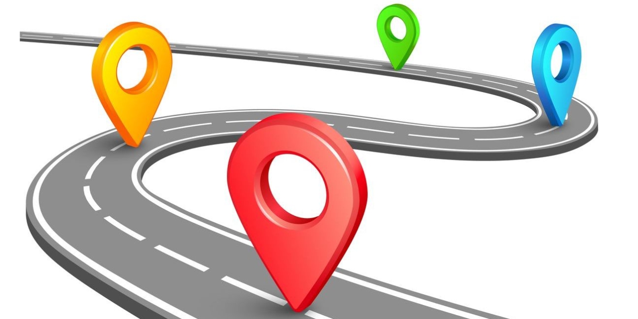 Illustration of four map pins which are coloured red, orange, blue and green, at regular intervals along a winding road