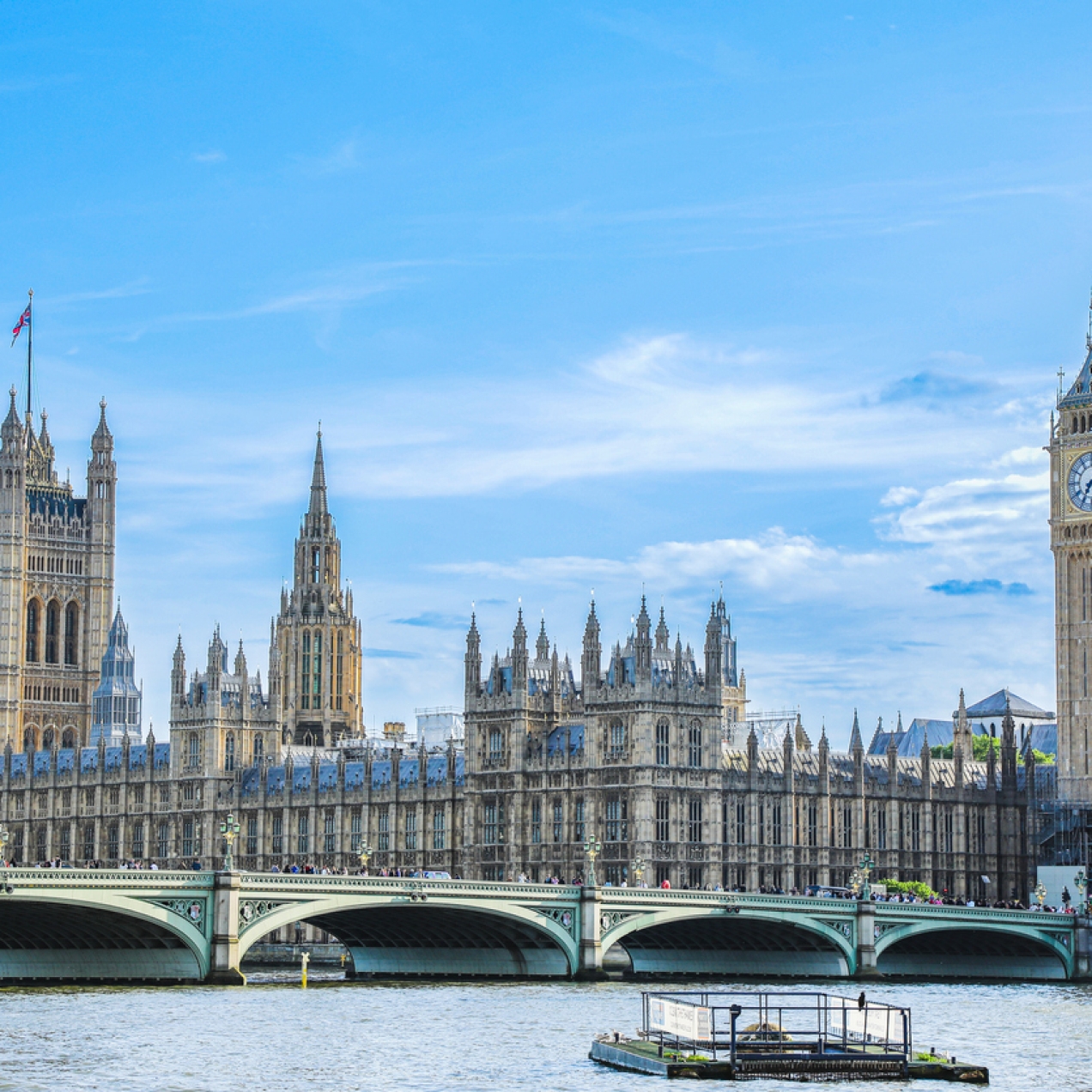 The Houses of Parliament, Westminster Bridge and Big Ben against a blue sky with few clouds and photographed from the south bank of London's River Thames
