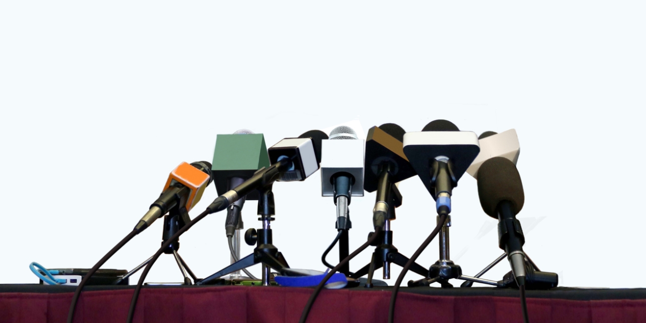 Eight microphones and three voice recorders on a desk
