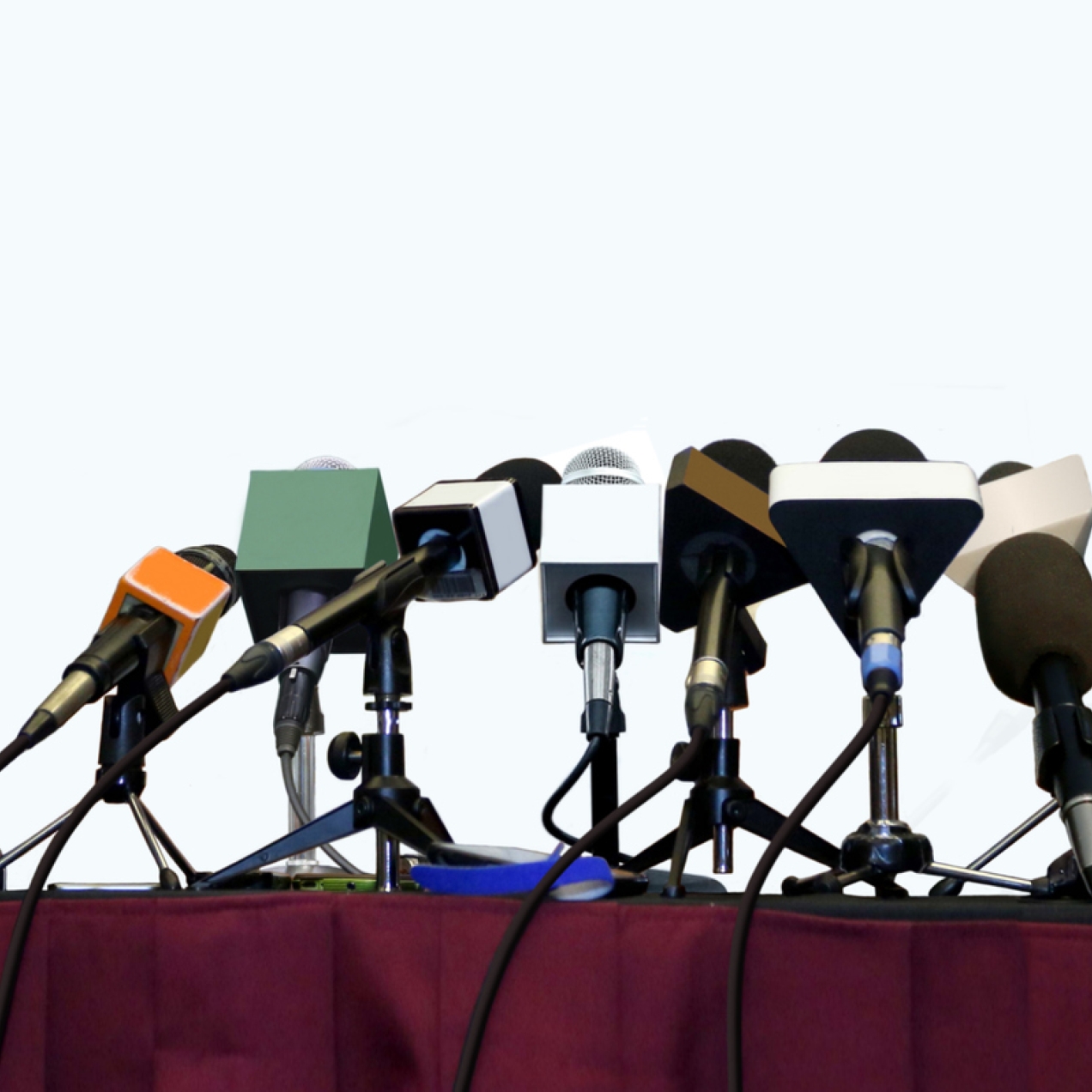 Eight microphones and three voice recorders on a desk