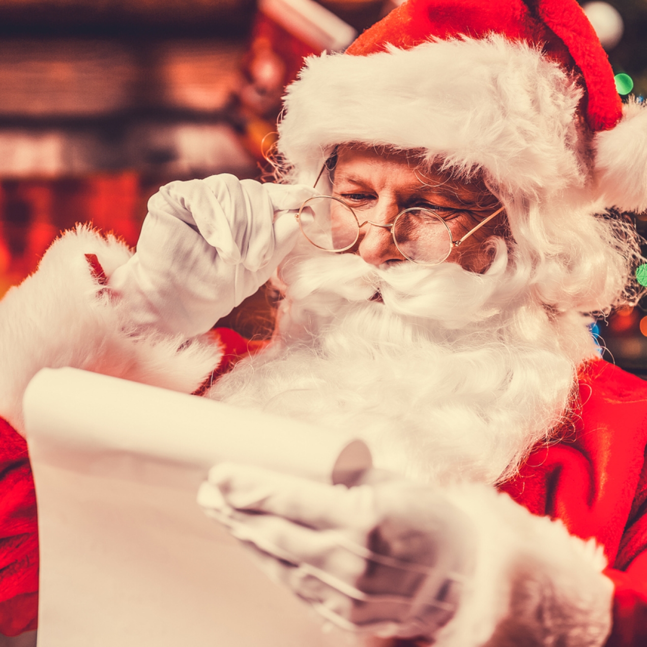 Father Christmas holding his spectacles as he reads a letter