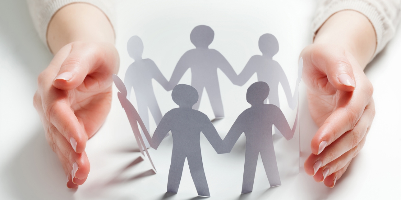 A circle of seven paper people cupped by two hands