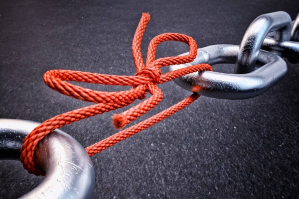 Metal chain links held together by red string