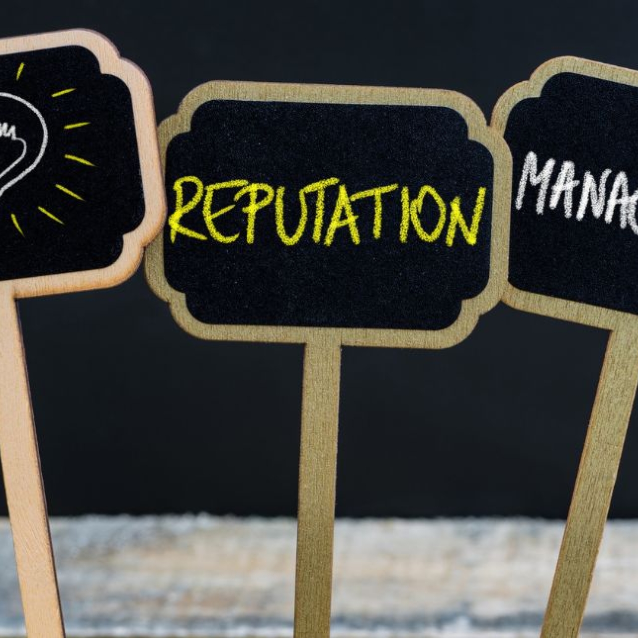 Three chalkboard signs in a row featuring a lightbulb illustration and the words reputation and management