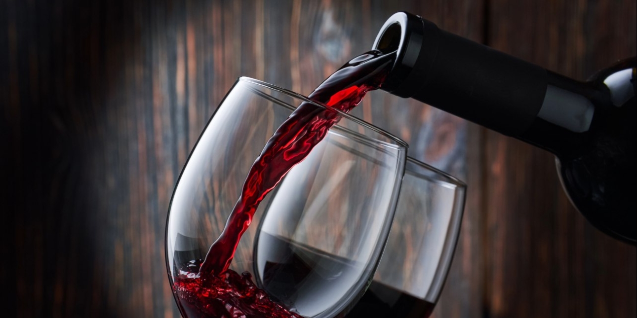 Red wine being poured from a bottle into two glasses.