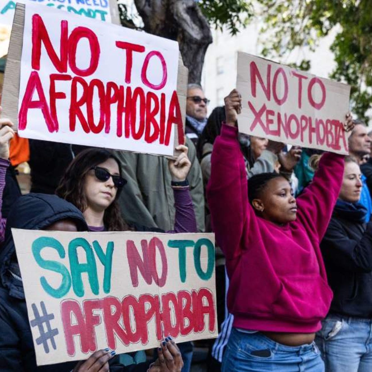 Activists hold up signs with messages urging against Afrophobia and xenophobia.