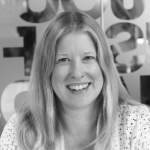 A black and white portrait of a smiling Caroline Klein. Caroline a white woman with shoulder length light-coloured hair.