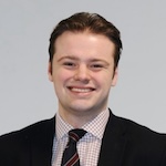 A head and shoulders photo of David Moore. Moore is a white man with short dark hair, who is wearing a dark jacket and tie.