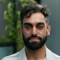 Head and shoulders of Sheeraz Gulsher. He has short dark hair and eyes, and a neatly trimmed dark bear. He wears a light blue jacket.