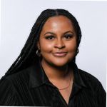 A portrait of Chynna Rhooms against a grey background. Chynna is a Black woman with long hair and wearing a black shirt