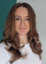 A colour portrait of Harriet Hernando, a white woman with long brown hair wearing a white top. The background is green and white