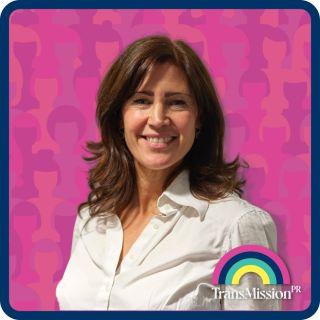 Portrait of Aby Hawker smiling and looking to camera. Any is wearing a cream blouse. The background is pink. A Transmission PR logo sits in the bottom right hand corner.