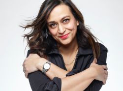 Portrait of Shilpa Saul, an Asian woman with dark shoulder length dark hair and red lipstick. She wears a black shirt and has her arms folded across her arms.