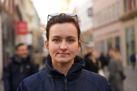 Erin Softley looking at the camera with glasses other head. Behind her is a busy high street which is blurred.