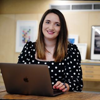 Shauna Madden, a white woman with shoulder-length dark hair, sat at at her laptop.